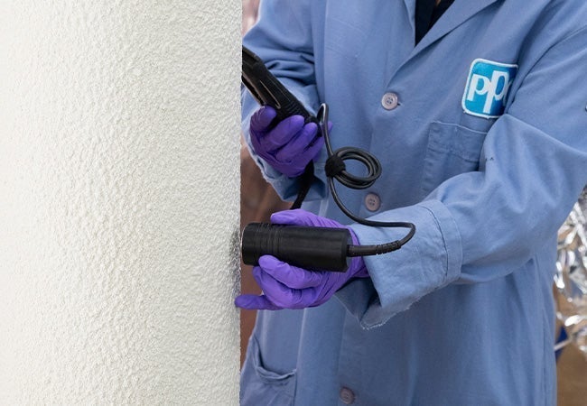 A person in a blue lab coat holding a black device