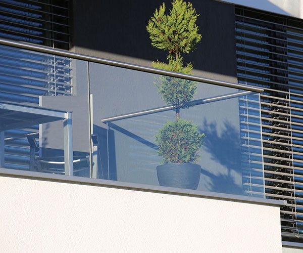 Balcony with glass structure and metal framing holding outdoor furniture and a green plant
