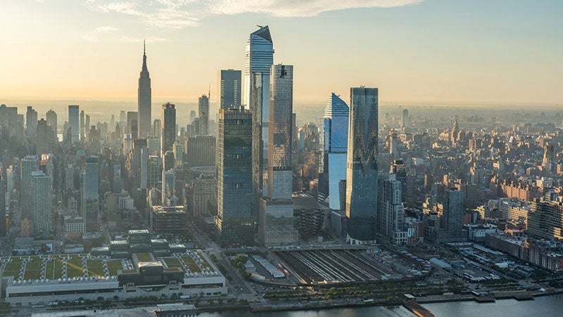 Aerial view of New York City skyline at sunrise featuring iconic skyscrapers and Hudson Yards