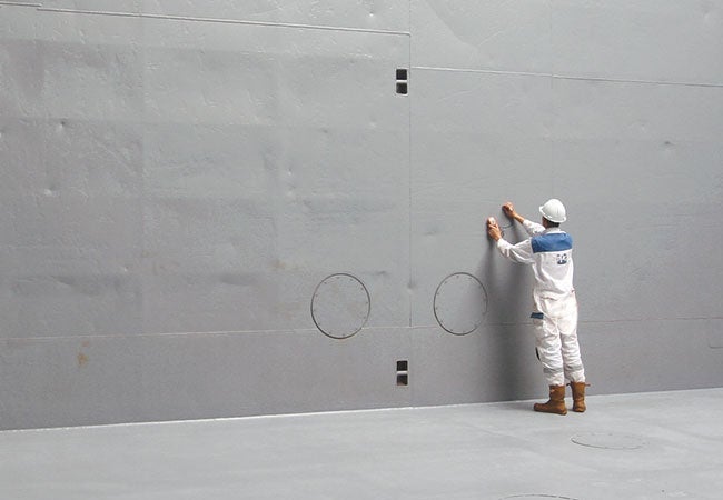 A man in white uniform and white helmet painting a wall