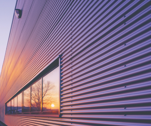 Violet coil warehouse with windows reflecting the sun and trees