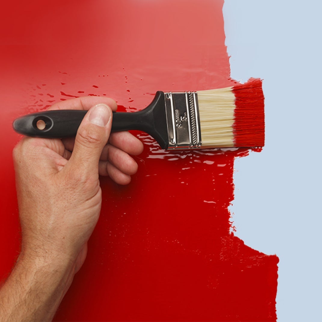 Male hand painting a wall in red paint