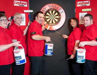 Several Leyland workers collaboratively painting a large dartboard.