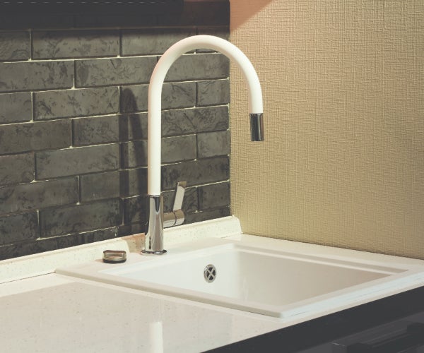 White faucet and basin against brown tiles