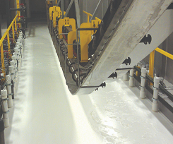 An electrocoat line moving over a bath or white liquid coating with yellow railings