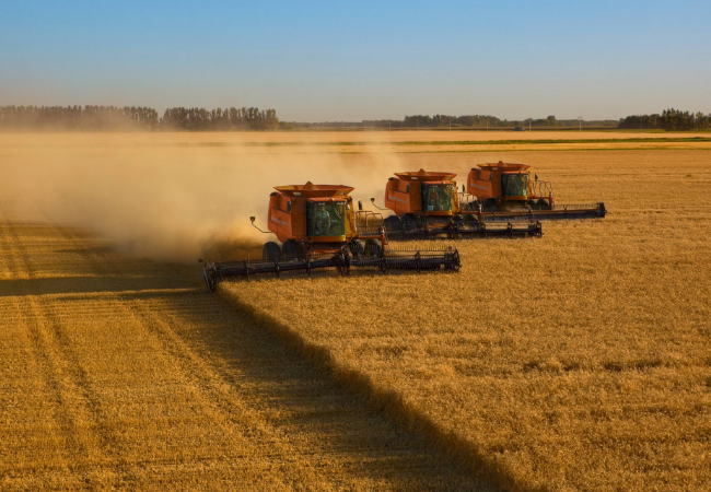 Three large pieces of red agricultural equipment in field