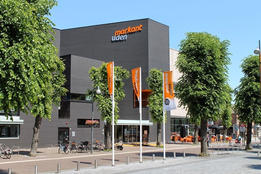 Een gebouw met oranje vlaggen en bomen