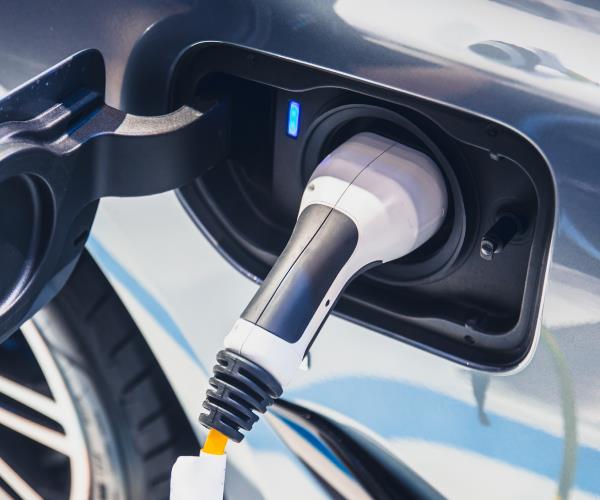 Close-up of an electric vehicle charging connector plugged into a car charging port, highlighting EV charging technology