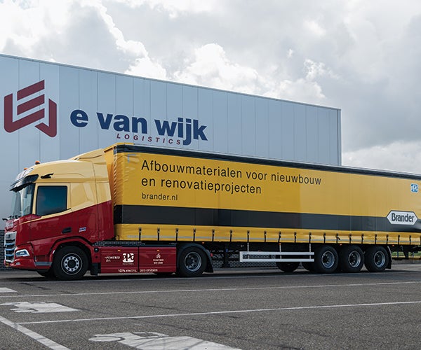 Large yellow lorry outside industrial building