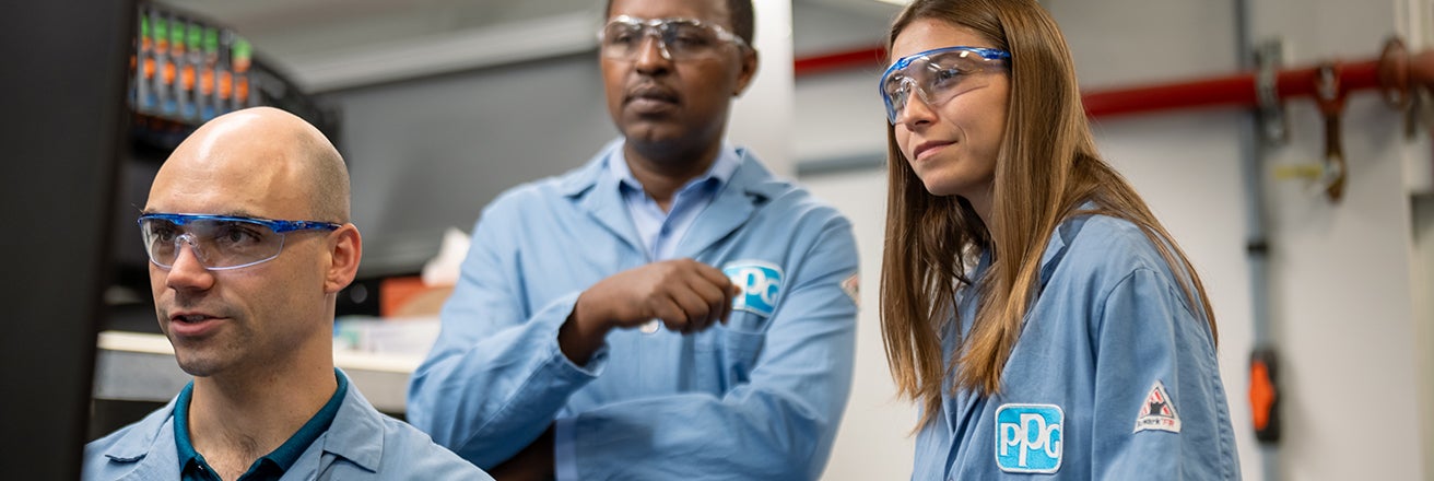 Male and female colleagues wearing PPE inspecting information on computer screen