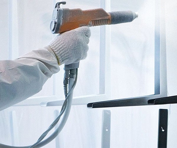 Hung metal component being sprayed with white powder