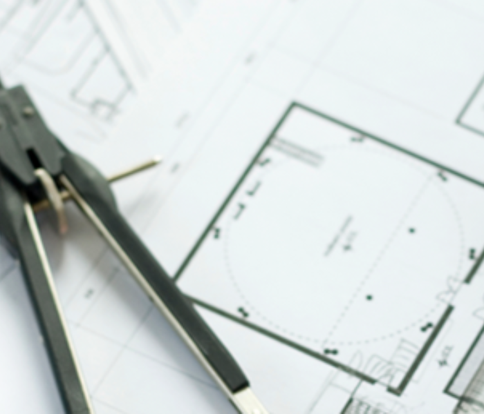 Close-up of an architectural blueprint with a drawing compass placed on top