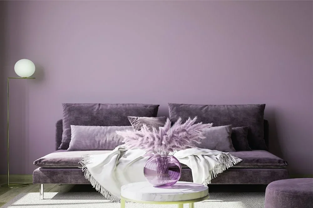Un sofá morado con un jarrón de flores sobre una mesa