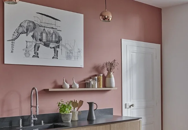 Une cuisine avec un mur rose et un tableau