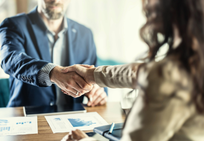 Man and woman shaking hands in business office over paperwork