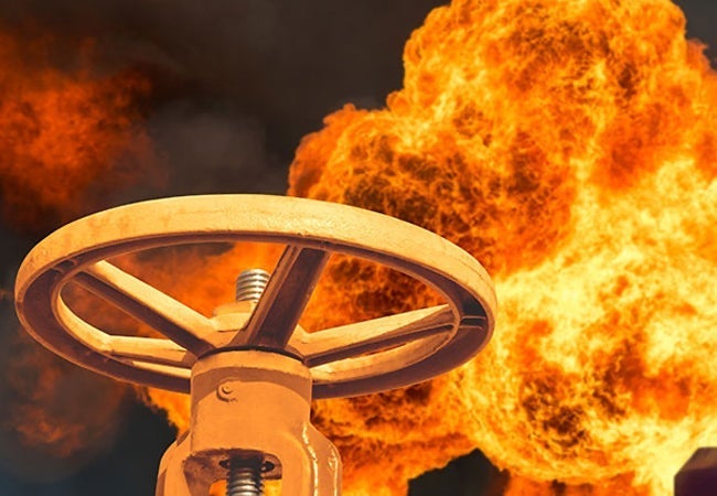 Large metal wheel handle coated orange next to flames