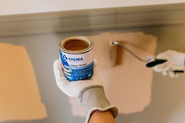 Een hand die een verfblik vasthoudt