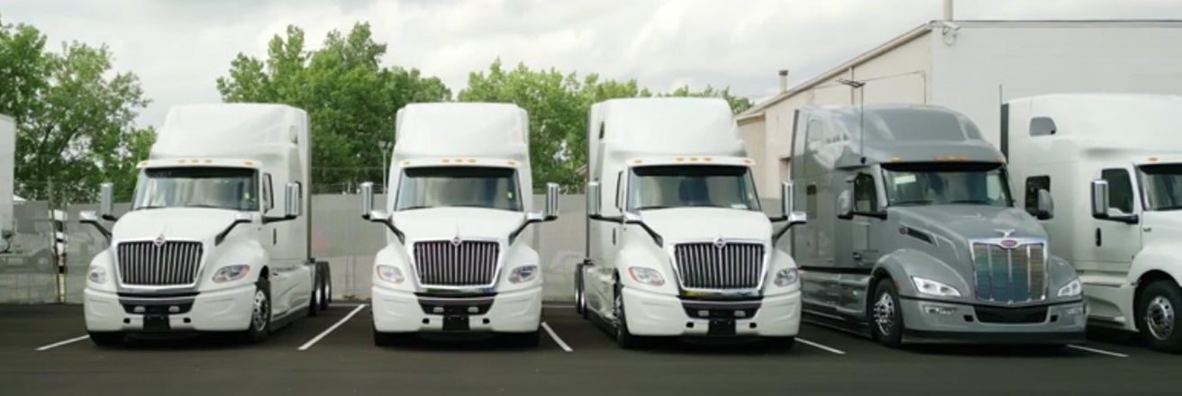 Series of white and grey trucks parked in a row