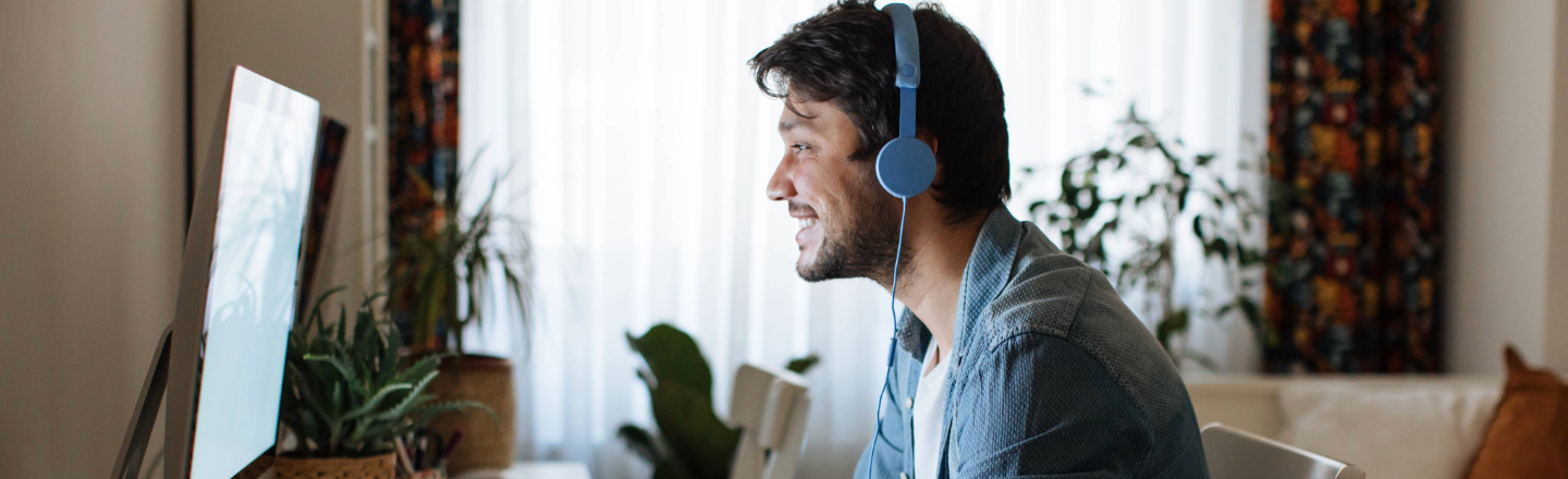 Man wearing blue headphones watching a video on screen