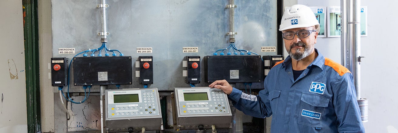 PPG team leader wearing PPE standing next to controls in factory