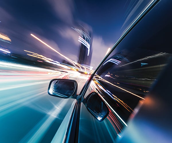 Car travelling past bright lights reflecting in body work and windows