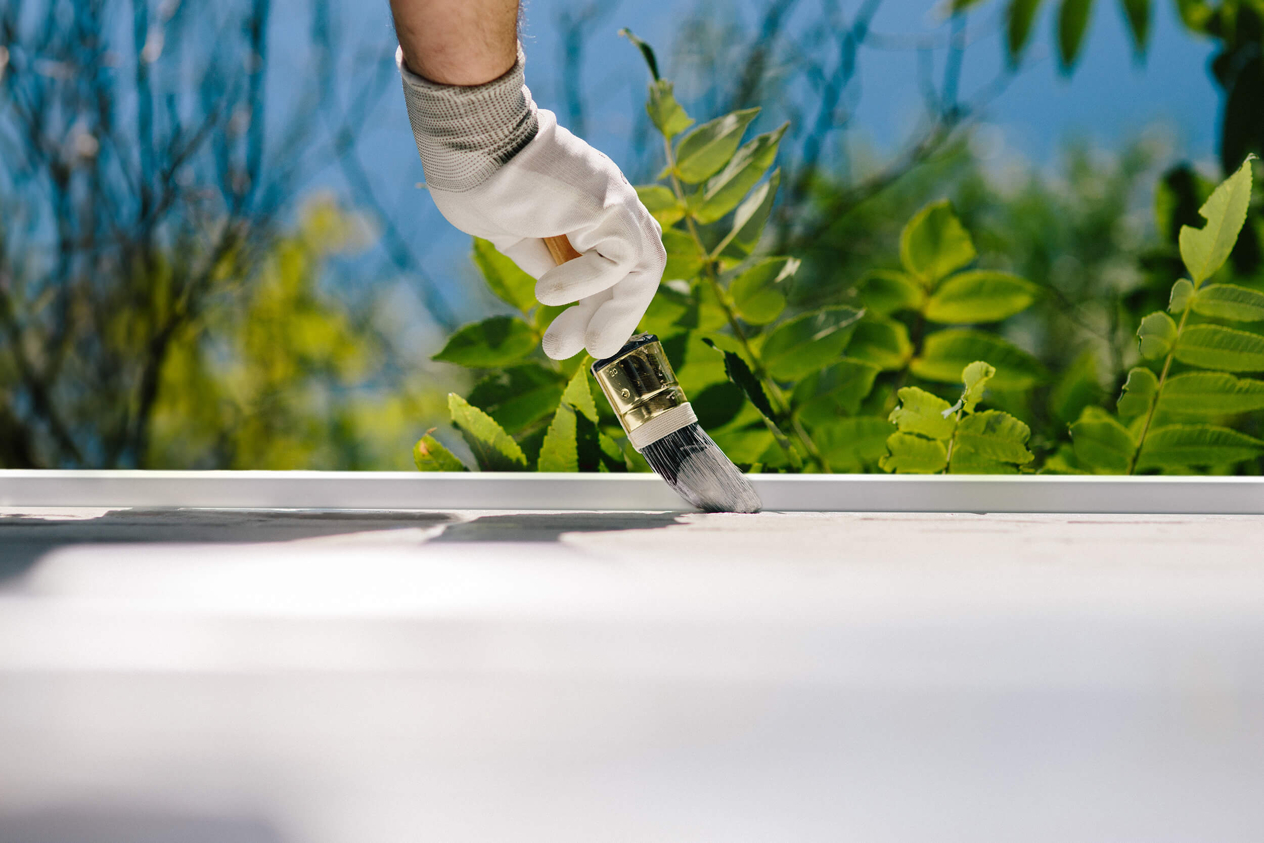 Een hand met handschoen die een wit oppervlak beschildert