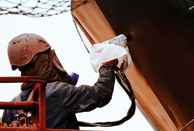 A person spraying a piece of metal