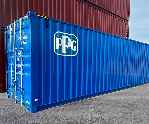 Close up image of a PPG shipping container sprayed in blue Envirocron powder. Set on the ground against a background of stacked shipping containers.