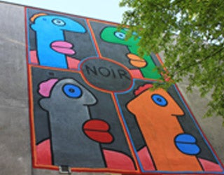 An abstract mural on a building featuring four heads arranged in a square, two on top and two below.
