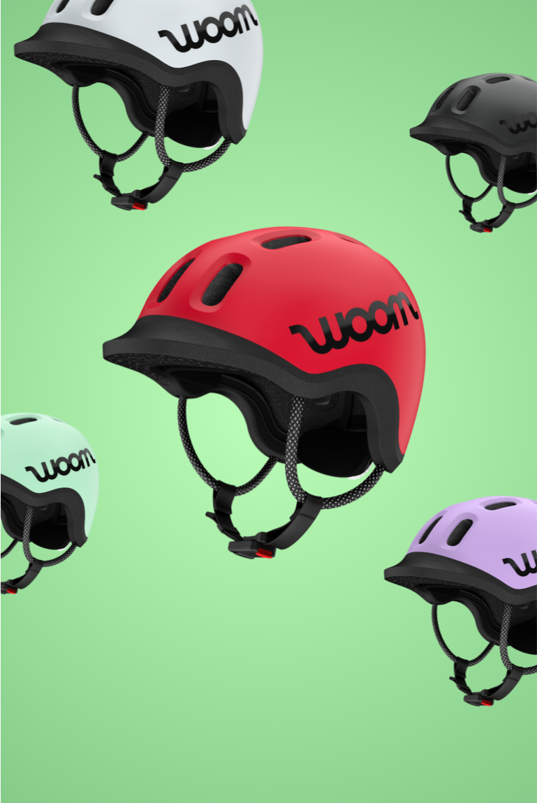 Casques READY de woom en 5 couleurs : woom red, mint, lilac, pale grey et charcoal metallic, arrière-plan vert