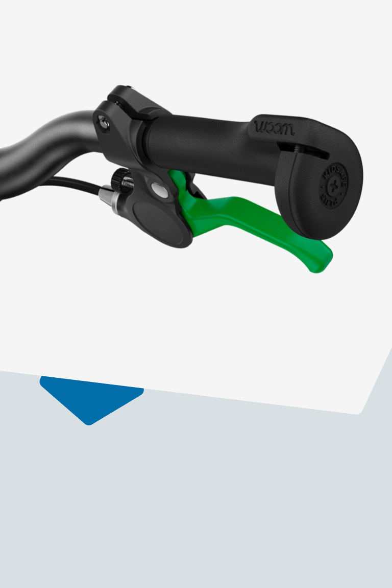 Close-up of the protective, oversize handlebar grip ends and green brake lever on a woom balance bike