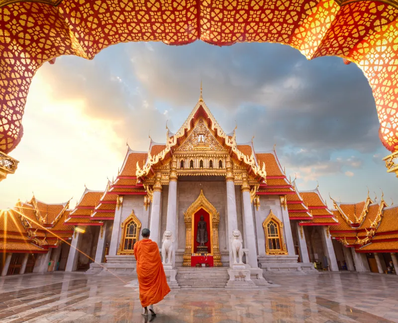A person walking in front of Wat Benchamabophit