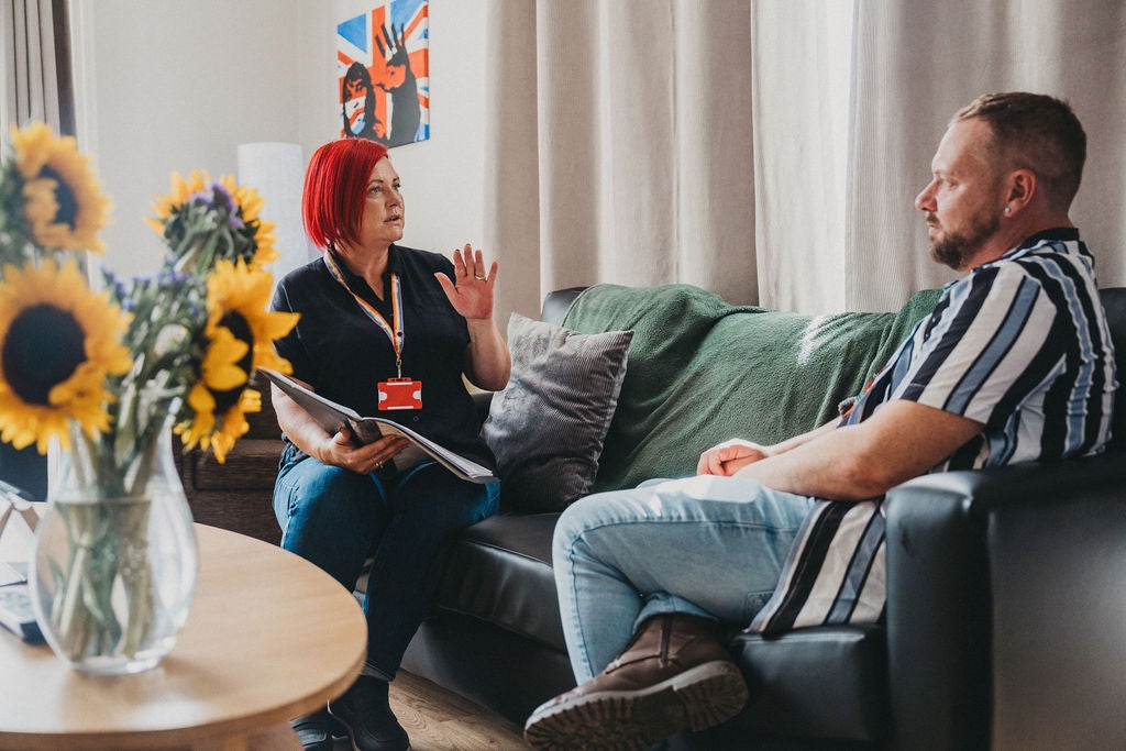 A woman talking to a man on a couch