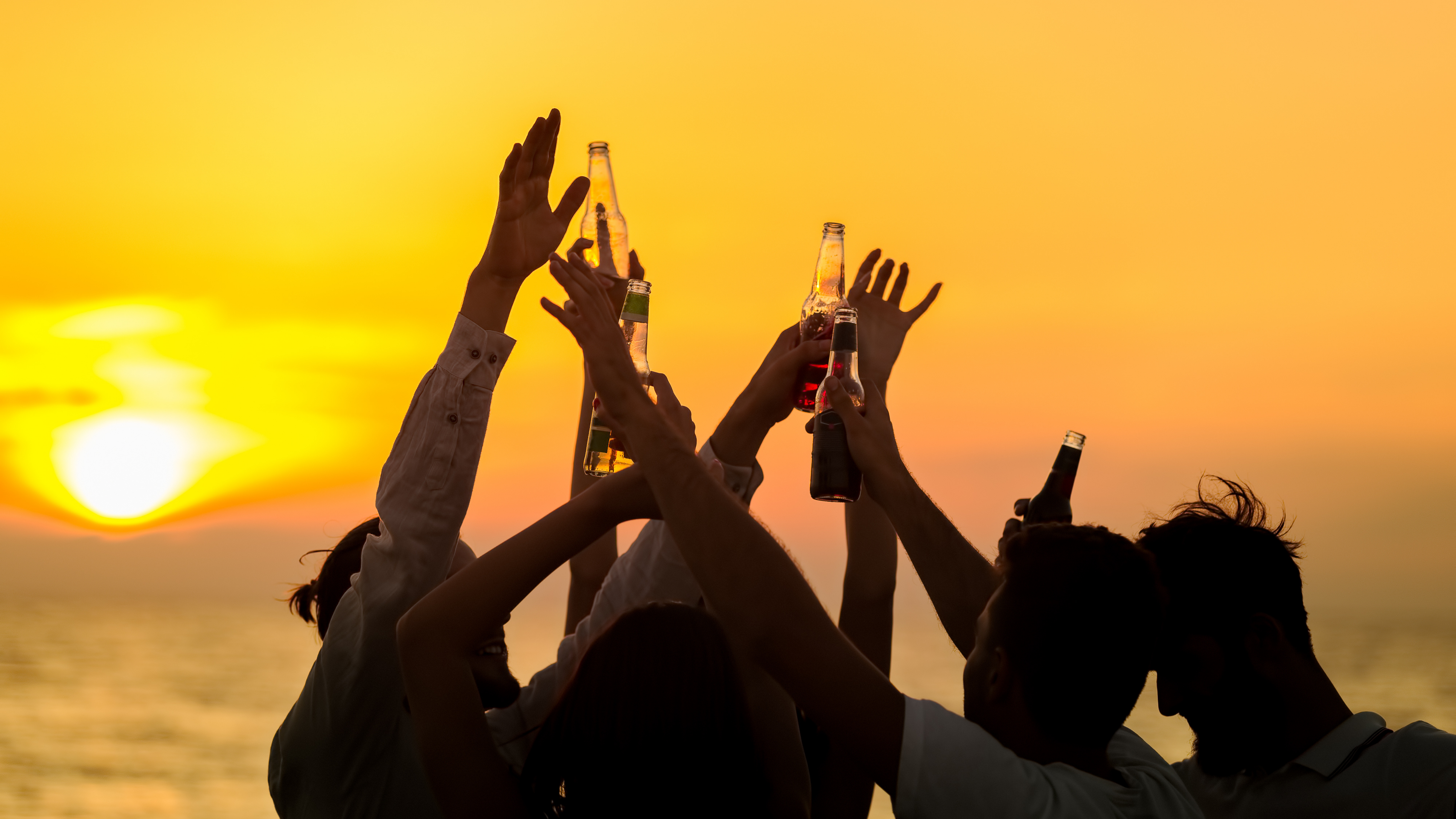 people drinking beer at the seaside at sunset