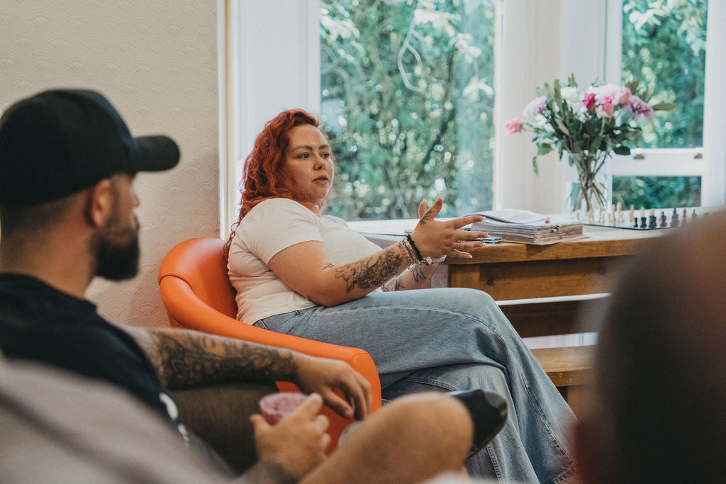 A woman sitting in an orange chair with a man in a black cap
