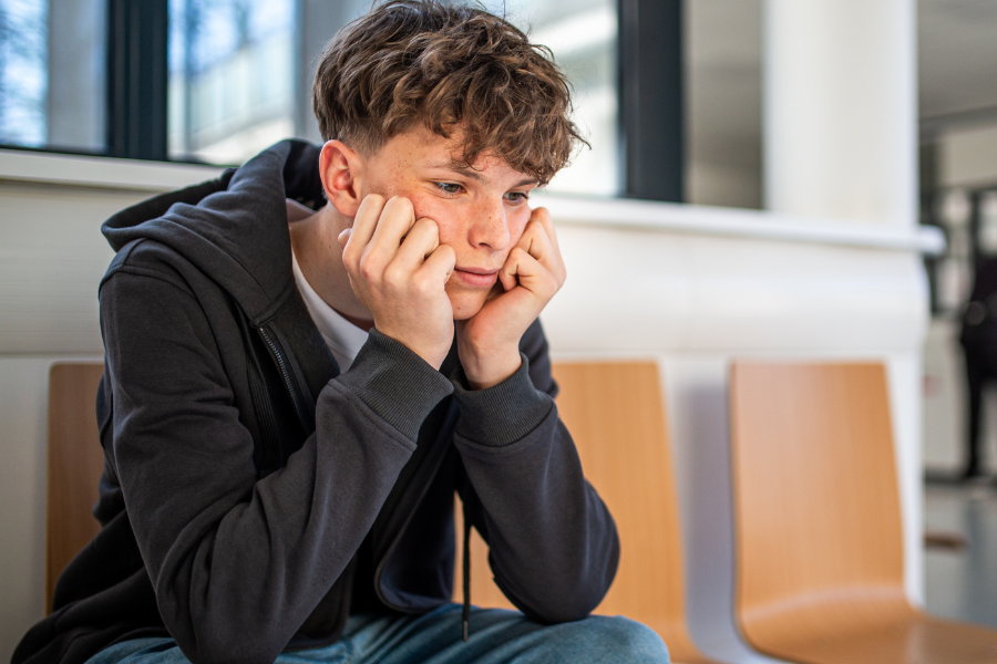 A boy sitting on a chair who looks worried. 
