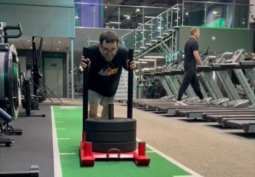 A man pushing a weight on a machine