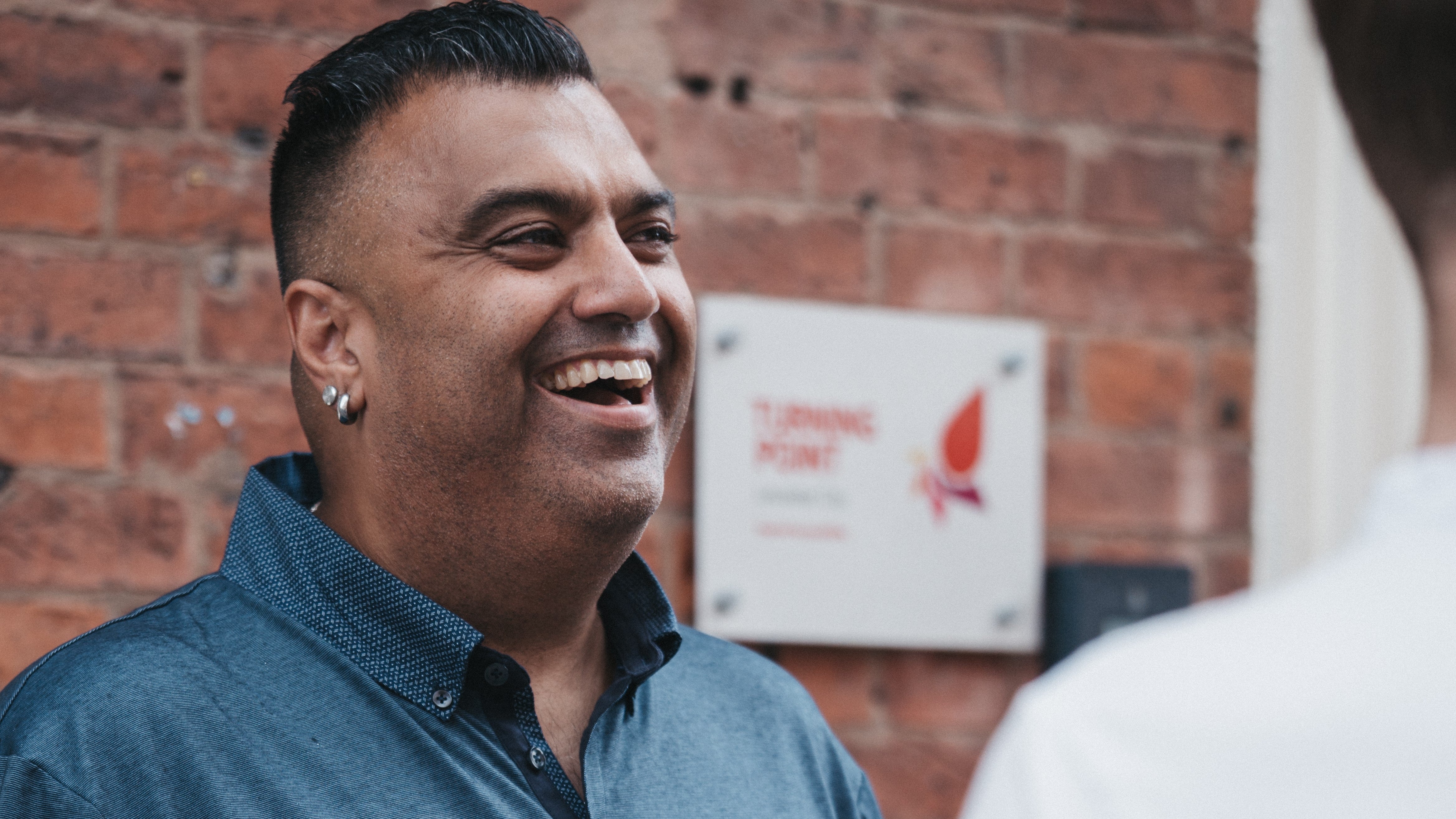 A man laughing in front of a brick wall
