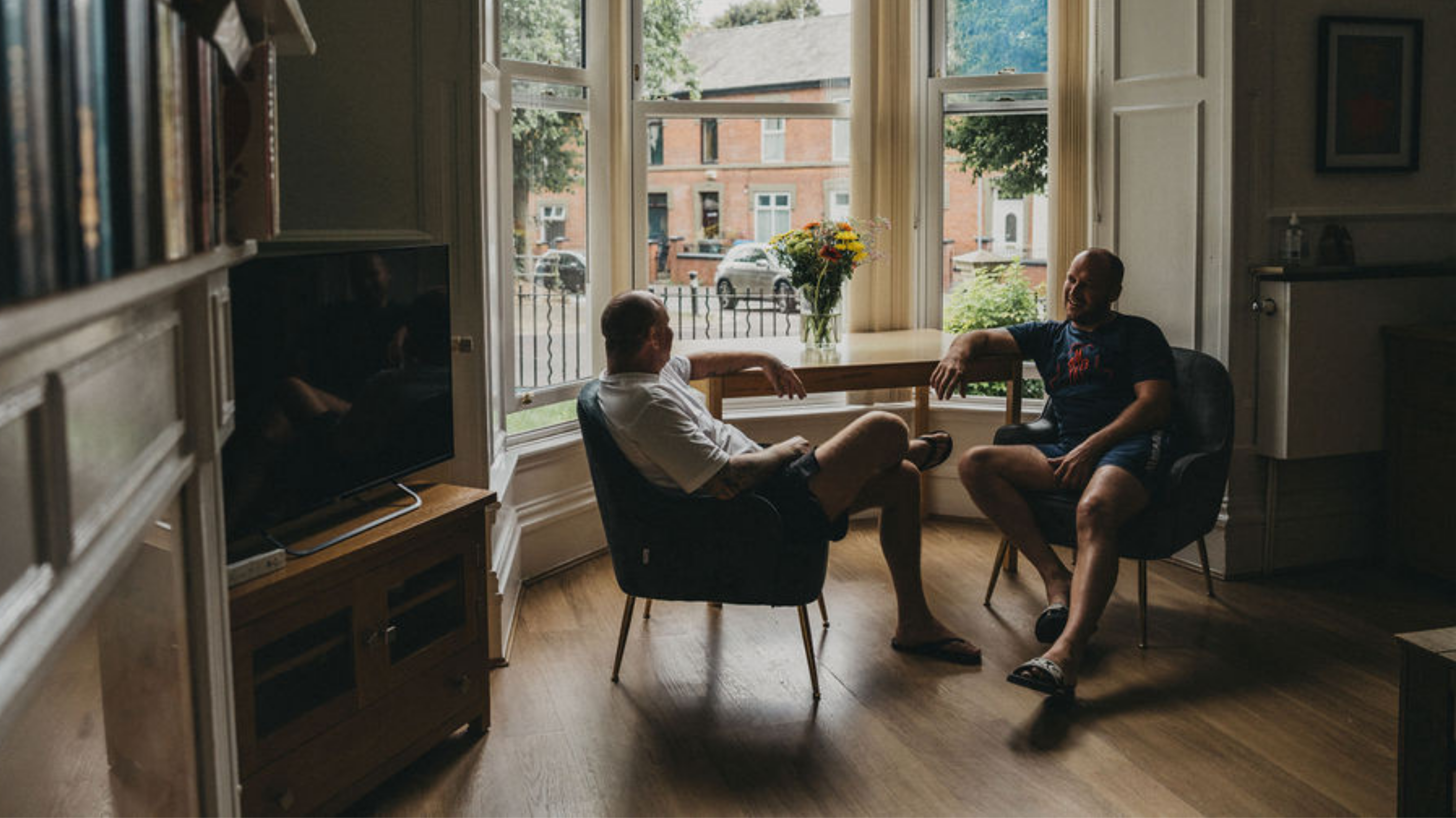 Two men sitting at window talking 