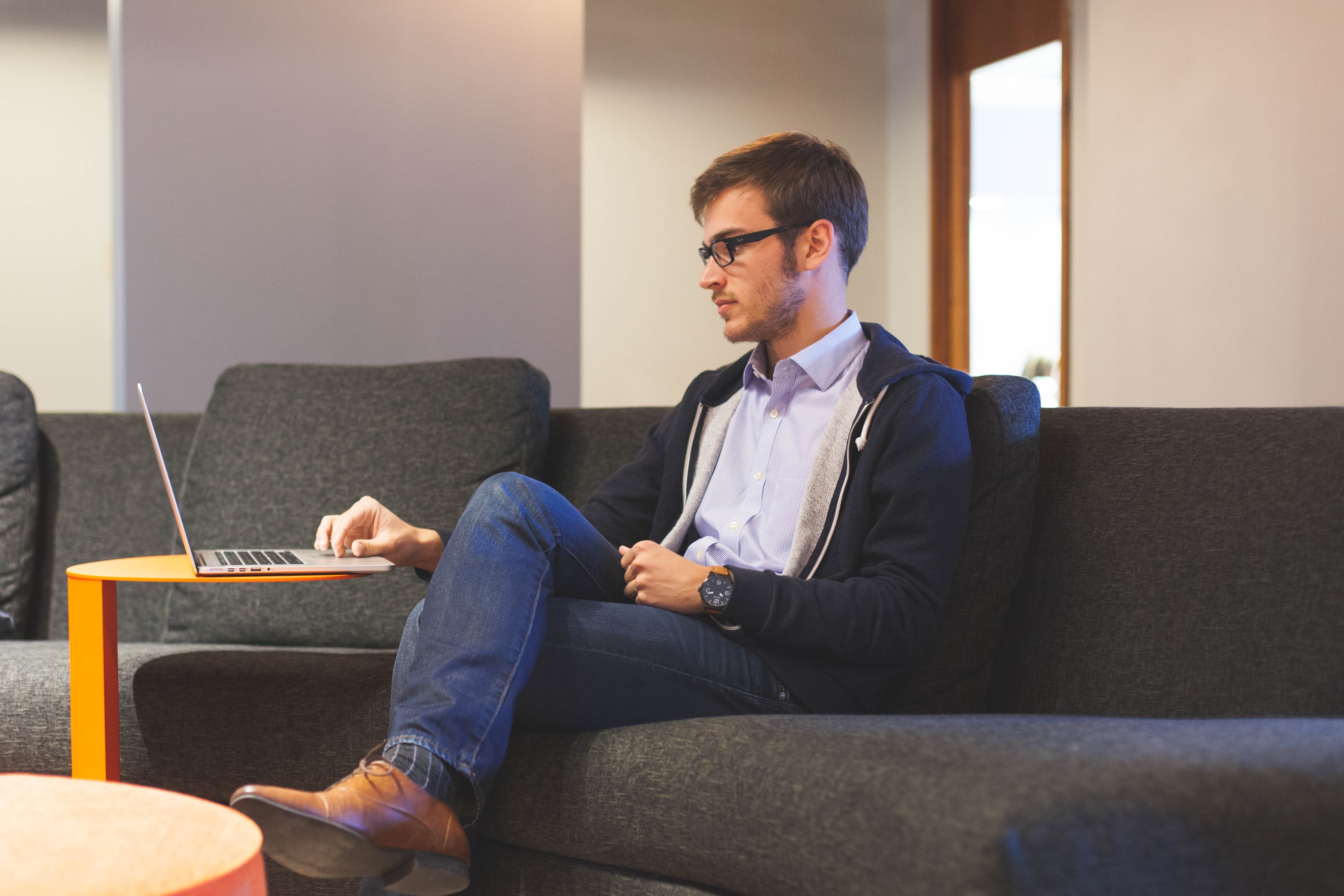 A man sitting on a couch with a laptop