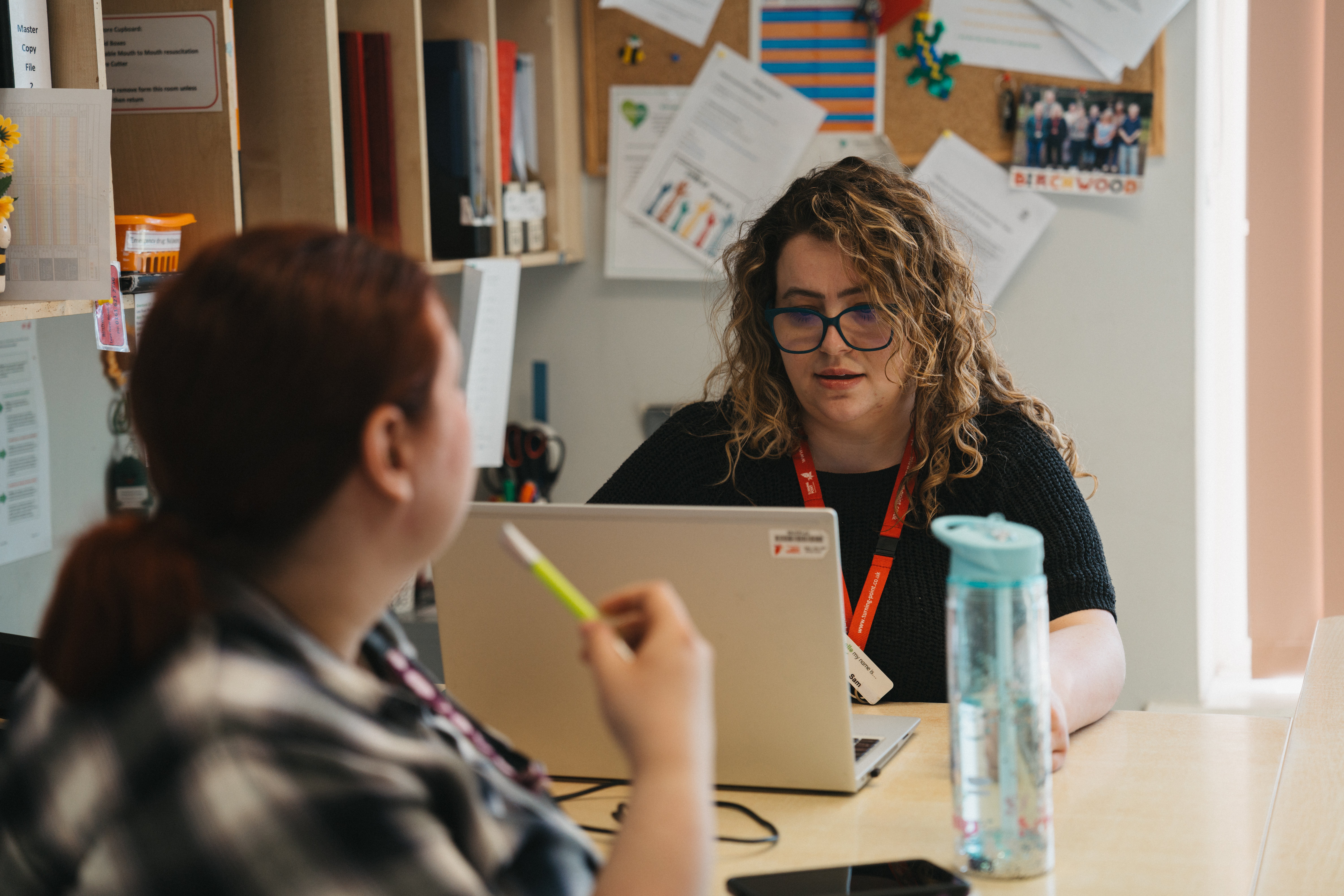 A woman sitting at a desktop typing on a laptop