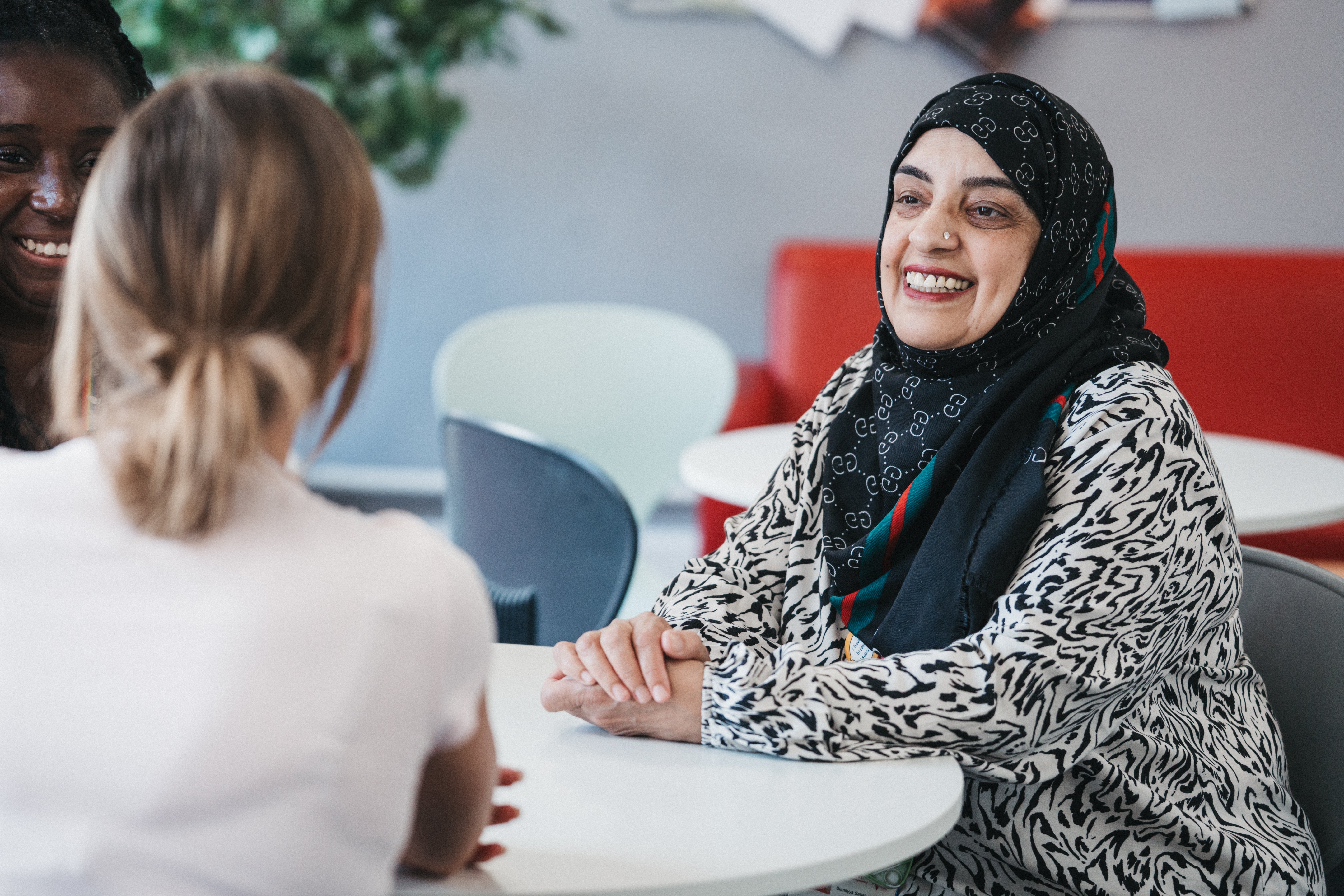 A woman sitting at a table with a woman in a head scarf