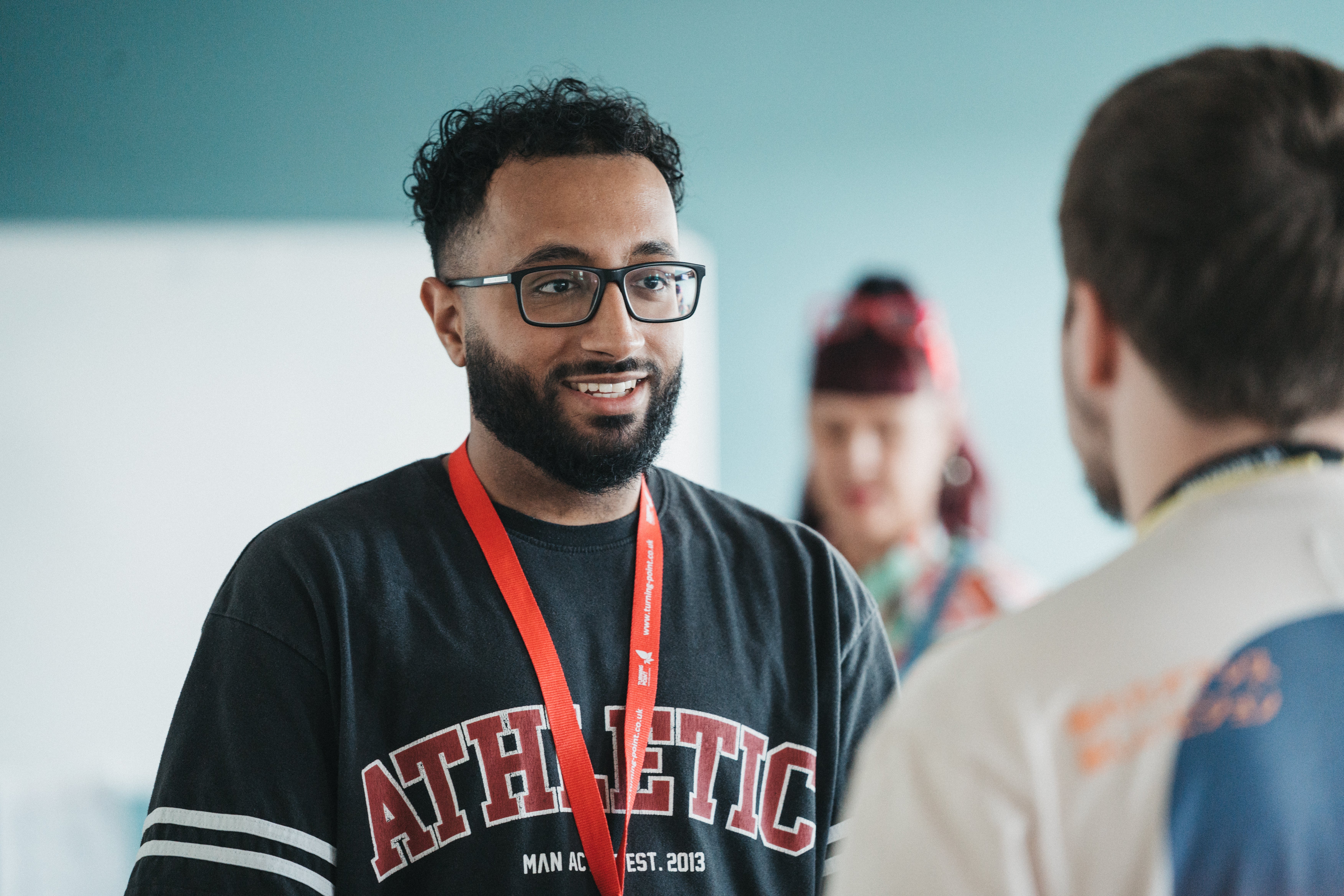 A man wearing glasses talking to another man