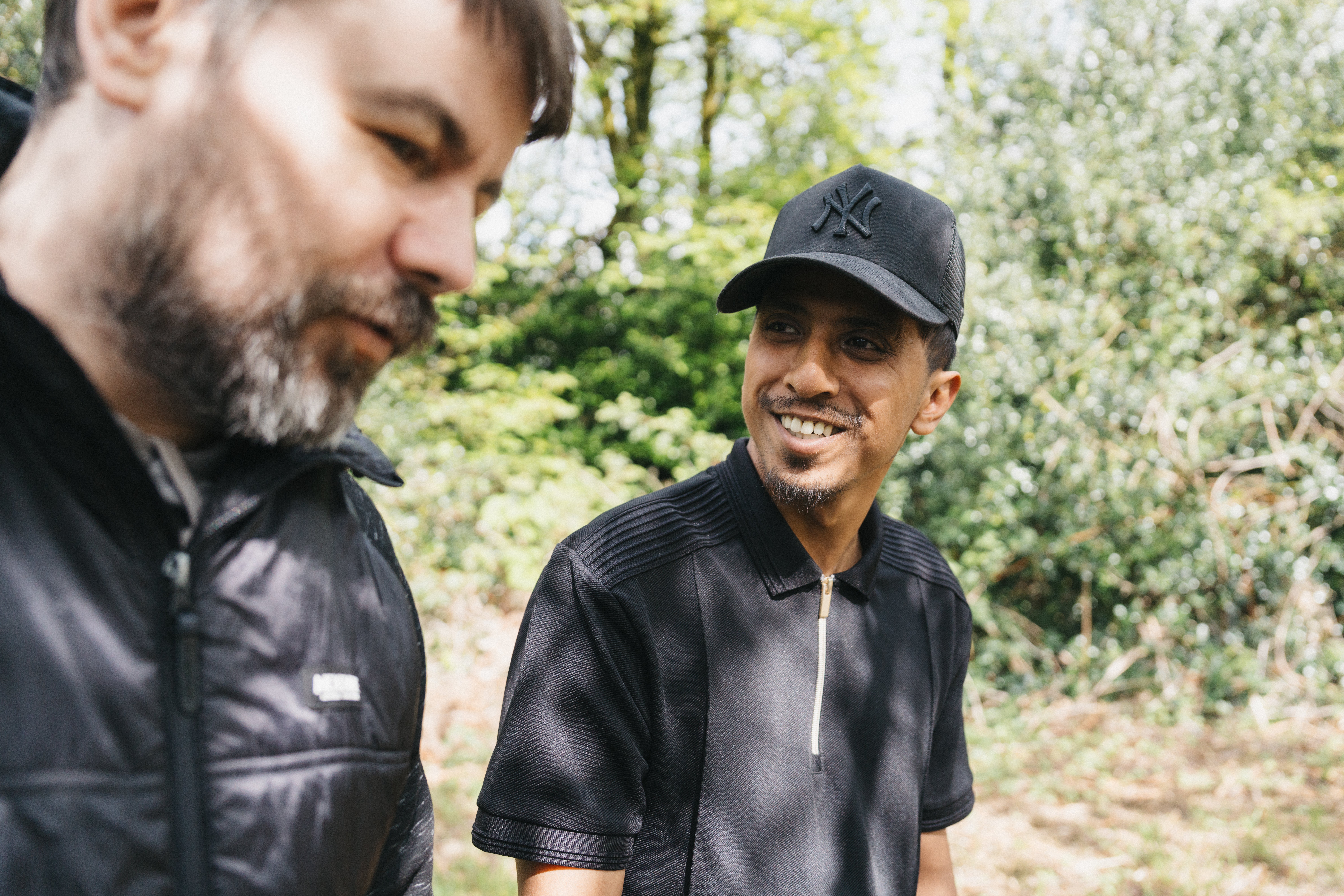 a man in a cap walking along talking to another man