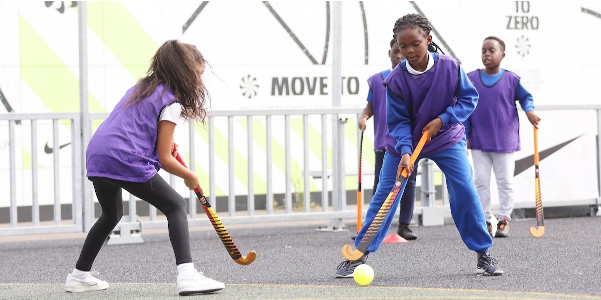 Girls playing hockey on a playground