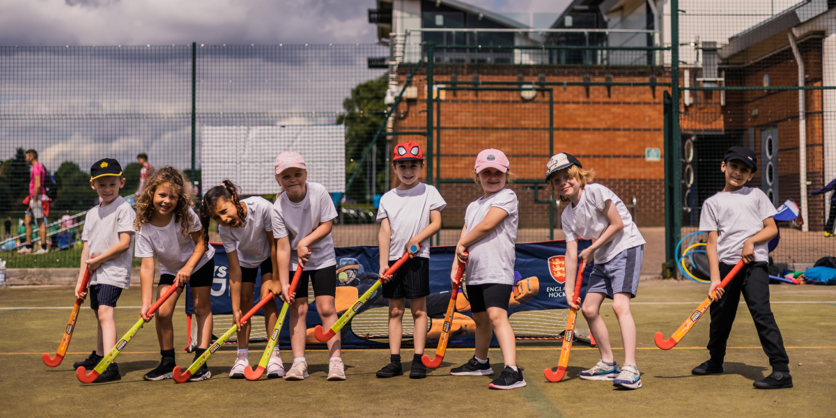 Children smiling holding hockey sticks