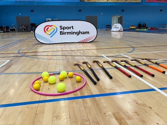 Sports hall with hockey sticks and hockey balls on the floor