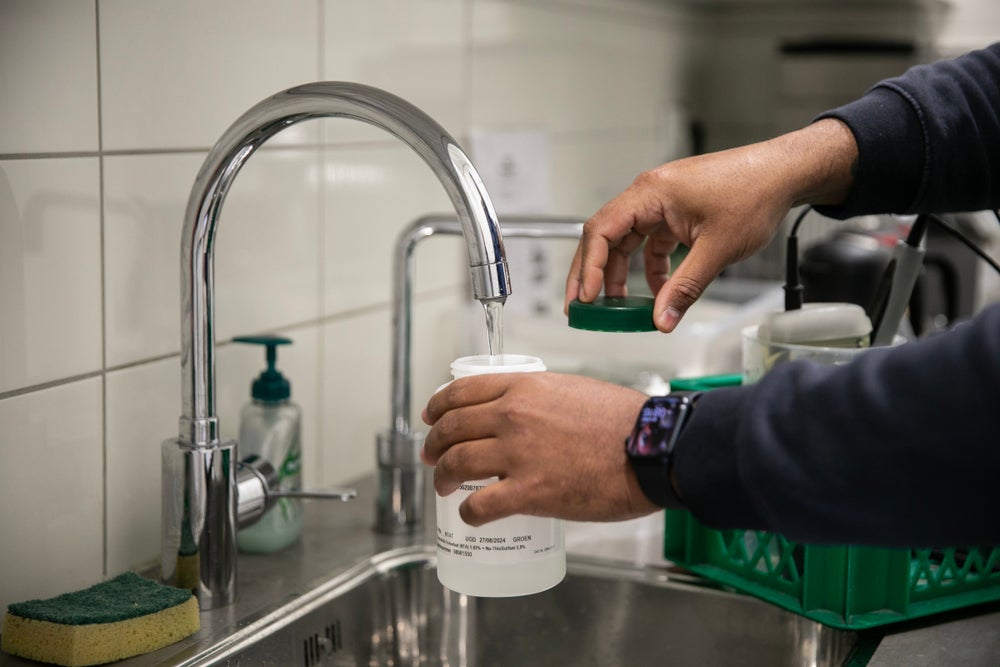 Evides medewerker vult een fles met water.