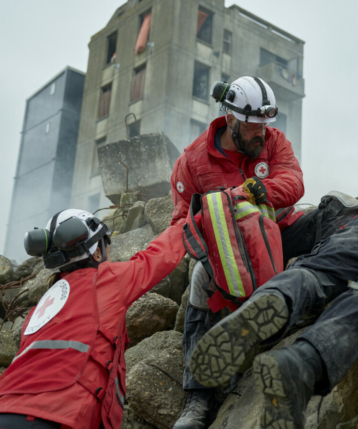 Red Cross workers search rubble to reach people caught in a disaster.