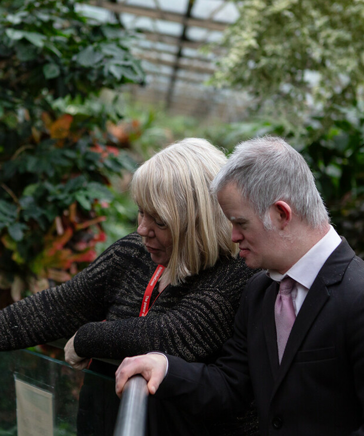 British Red Cross support worker with a young man she supports in a greenhouse.